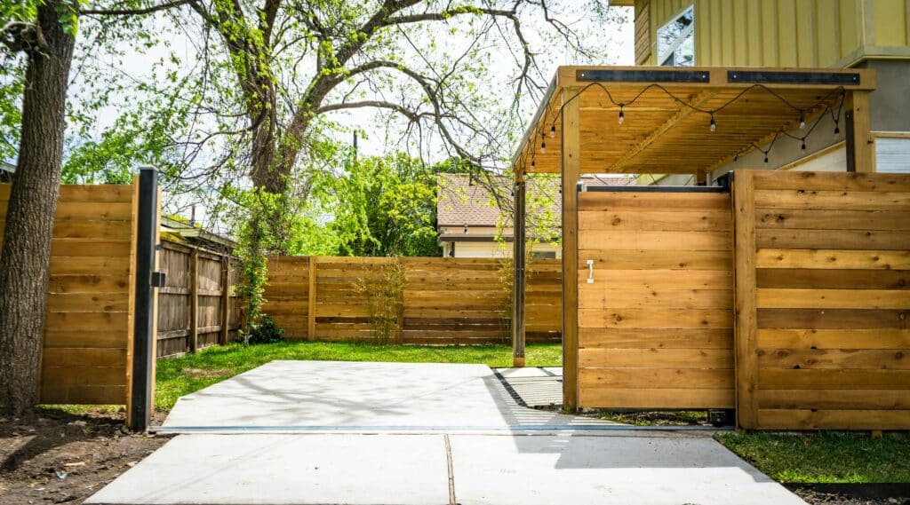Aménagement extérieur moderne : patio, pergola & clôture bois Sunlit wooden fence and patio gate in a peaceful backyard setting.